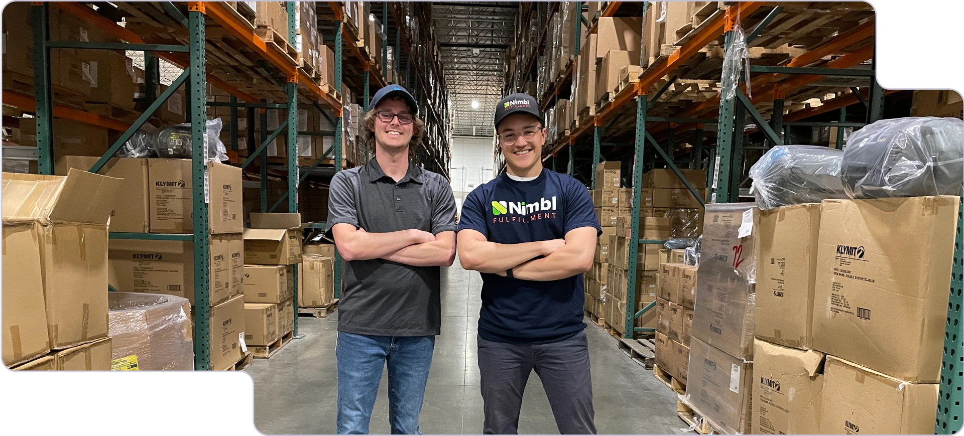 Two people in a warehouse, smiling at the camera