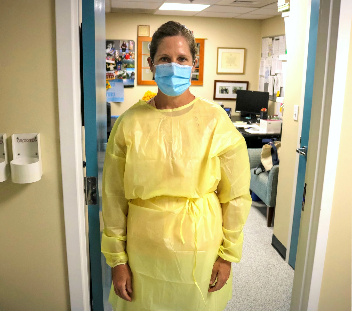 A woman wearing scrubs and a mask